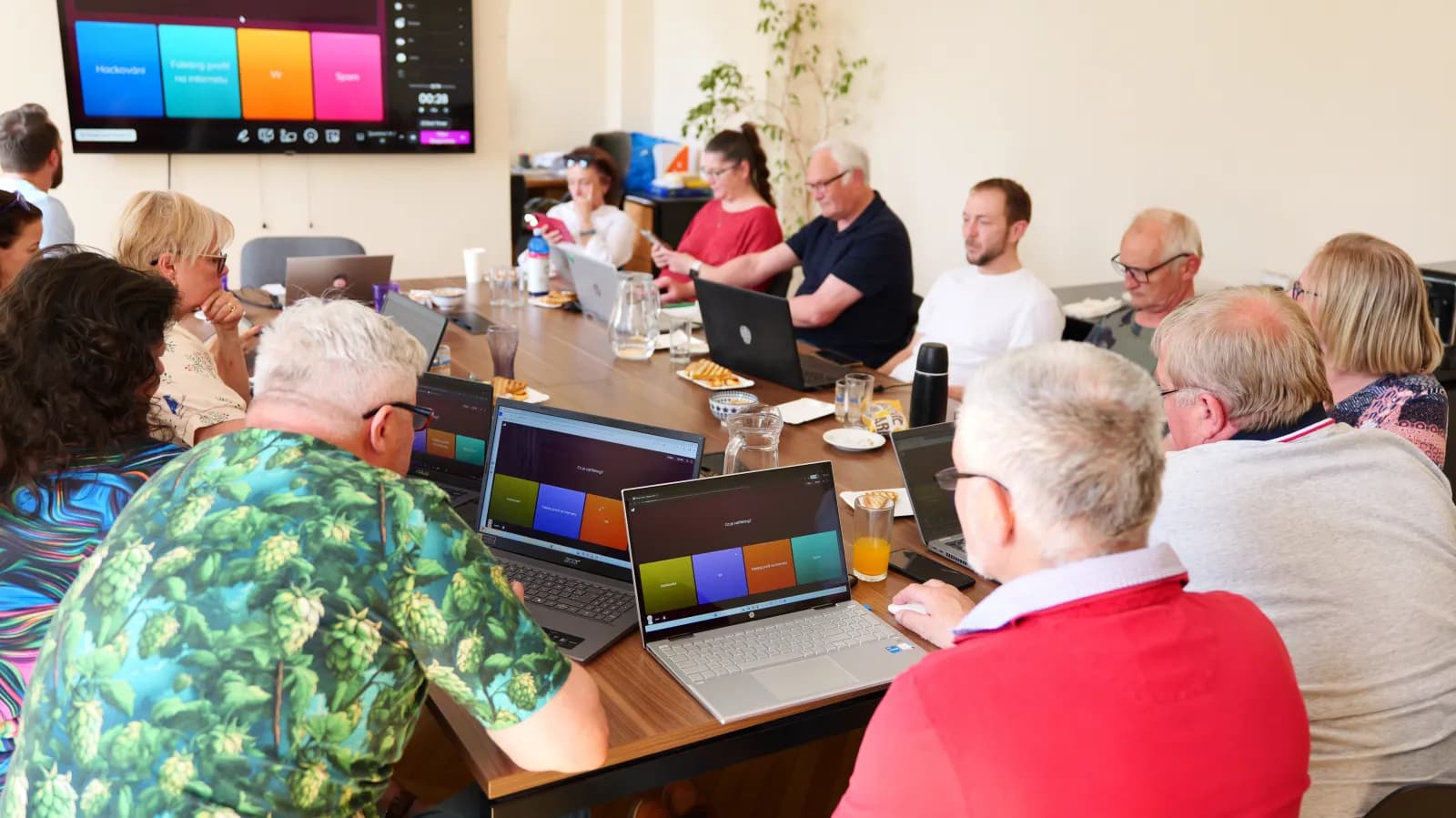 Senioři na kurzu digitální gramotnosti u společného stolu