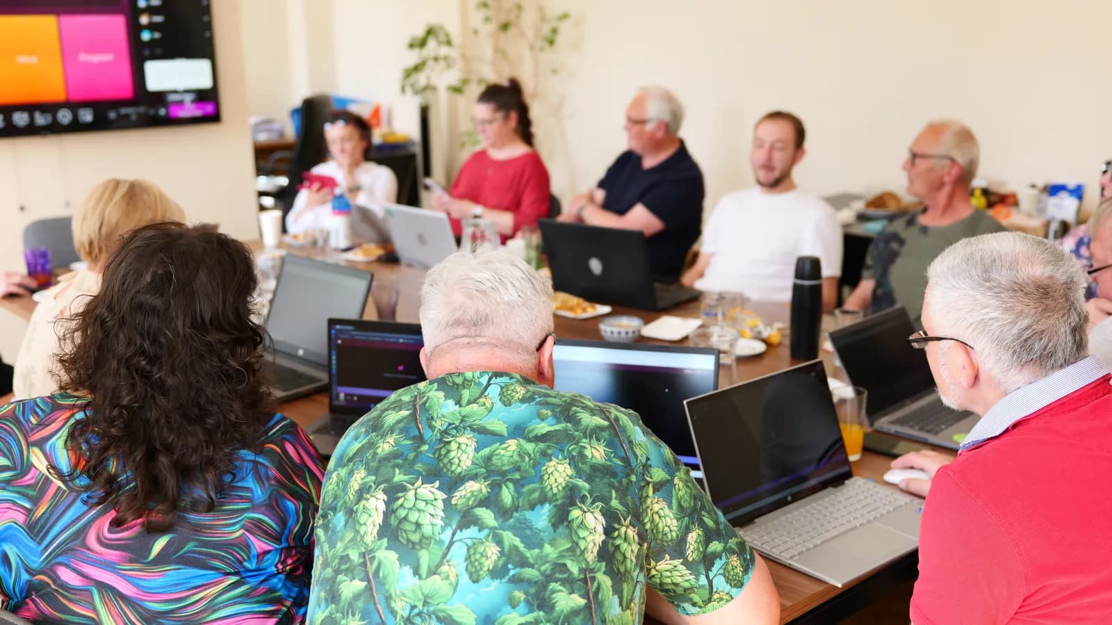 Účastníci kurzu pracují na noteboocích u společného stolu